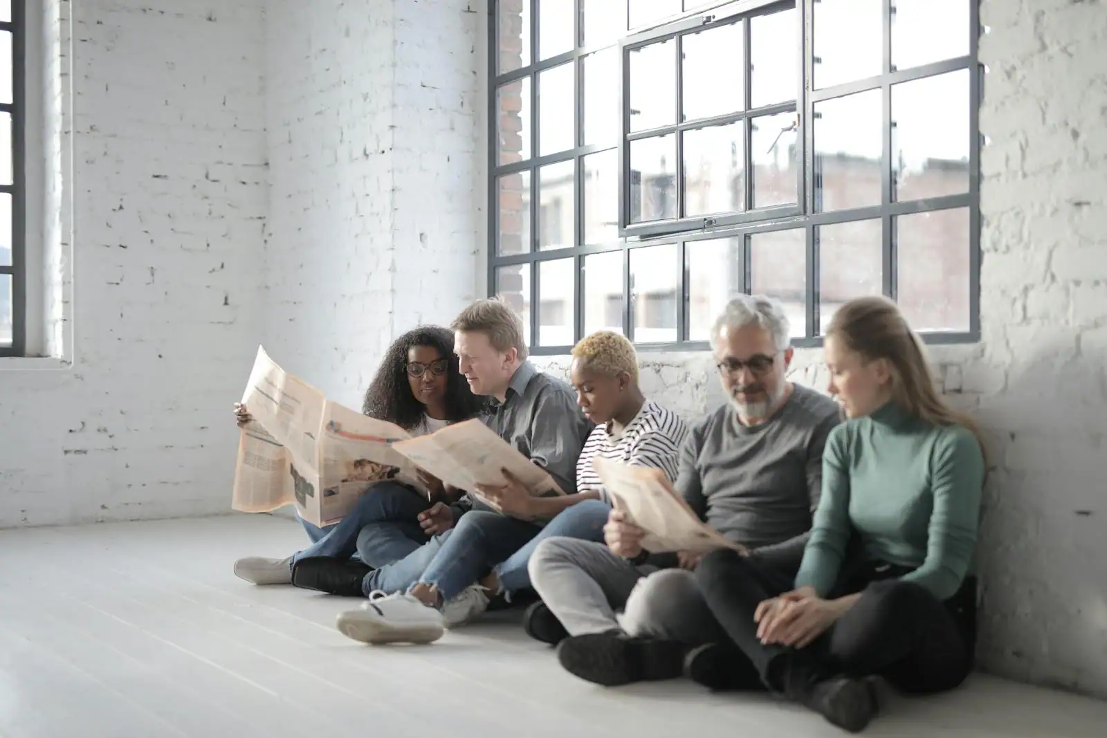 Une personne lit la presse économique attablée près d'une fenêtre lumineuse