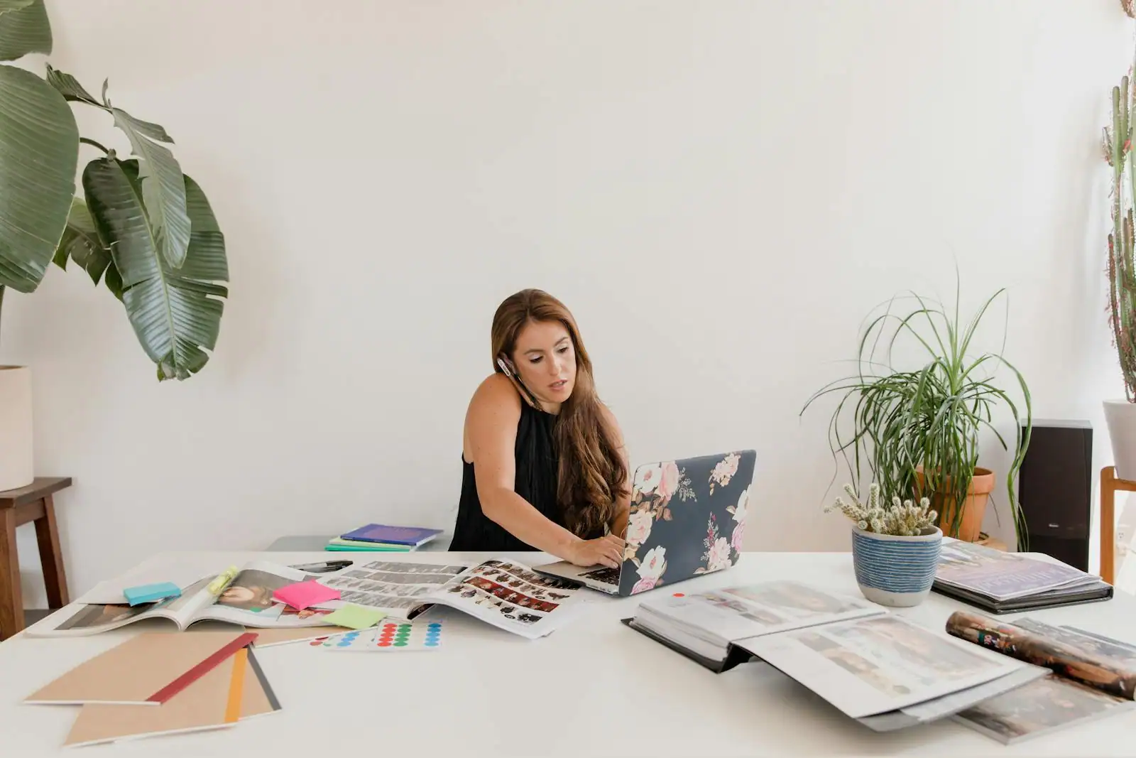 Auto-entrepreneure travaillant sur un ordinateur portable à son bureau couvert de documents de travail