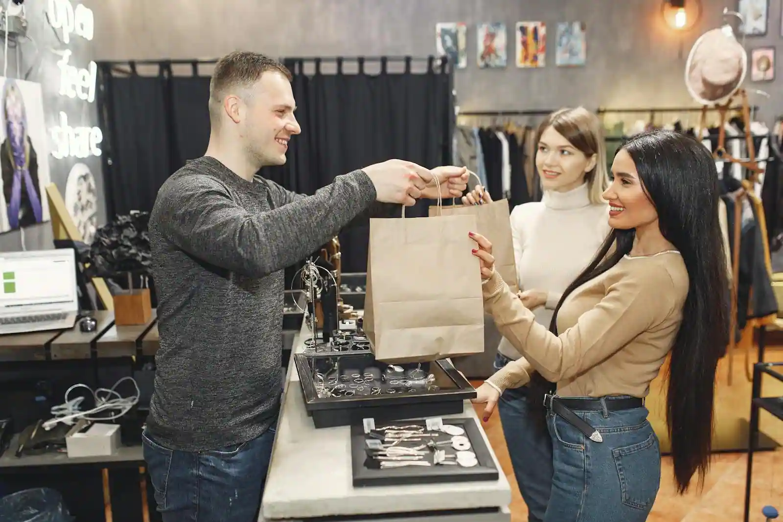 Un vendeur remet un sac d'achat à une cliente au comptoir d'une boutique