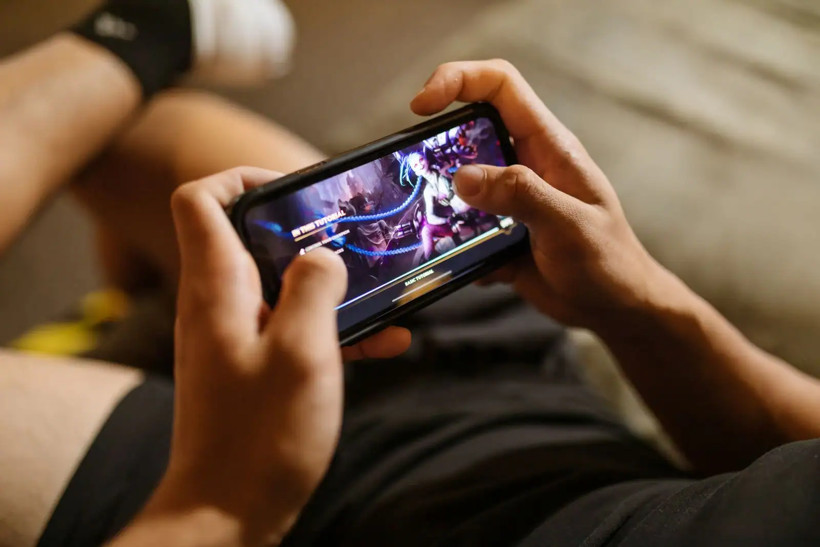 Personne tenant un smartphone à deux mains et jouant à un jeu mobile, illustration d'un jeu sur écran
