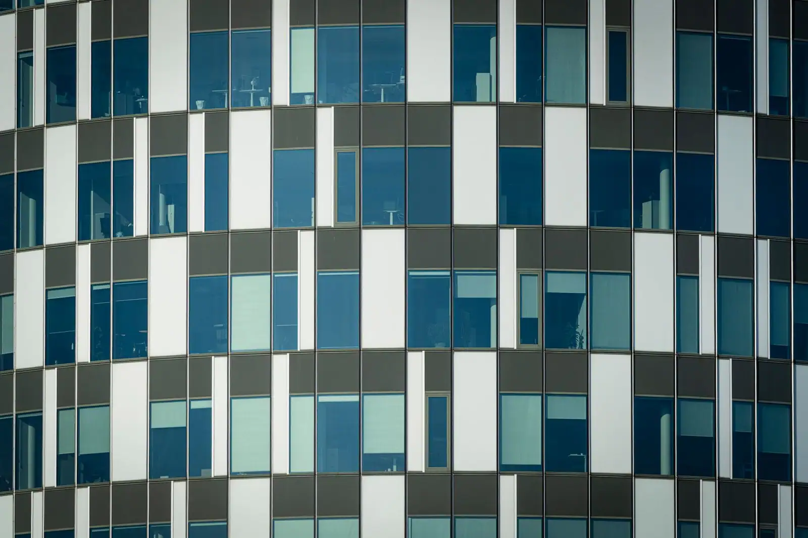 Façade vitrée d'un immeuble de bureaux moderne, rythmée par ses nombreuses fenêtres alignées