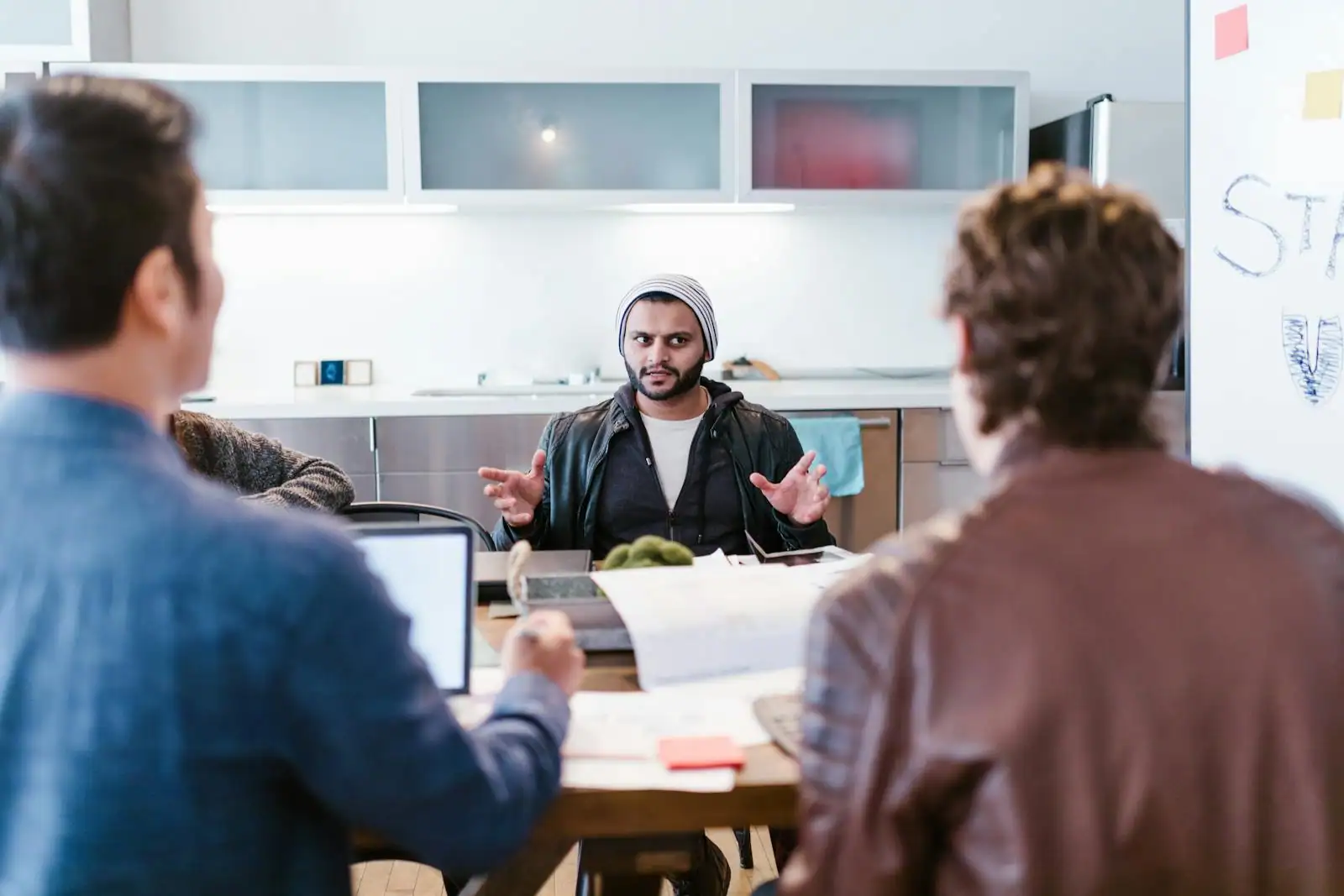 Une équipe communication échange autour d'une table de réunion dans un bureau lumineux