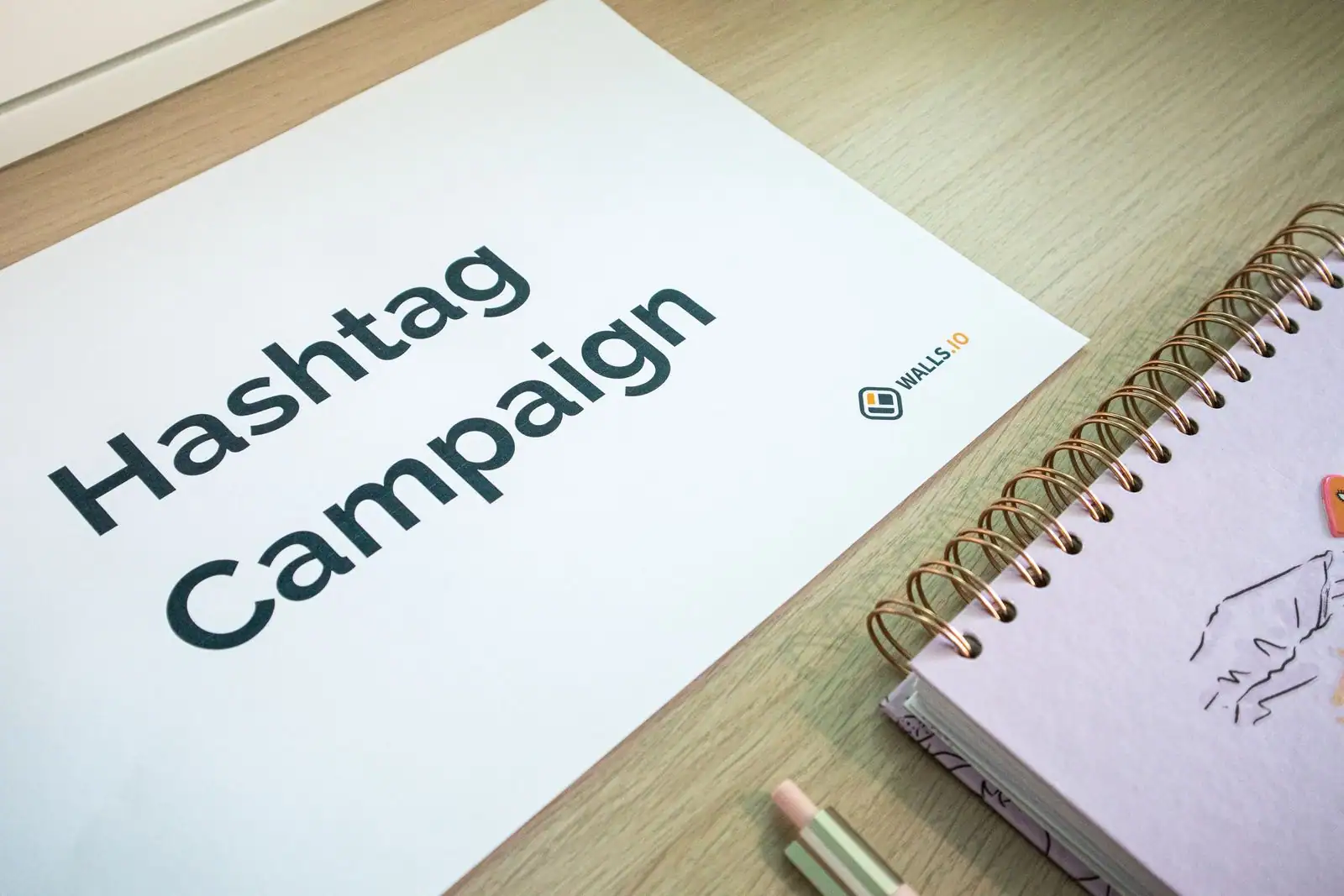 Document imprimé titré « Hashtag Campaign » posé sur un bureau, à côté d'un carnet à spirale et de crayons