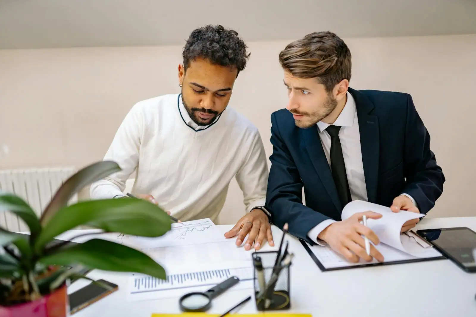 Deux professionnels de métiers différents échangeant autour de documents techniques dans un bureau.