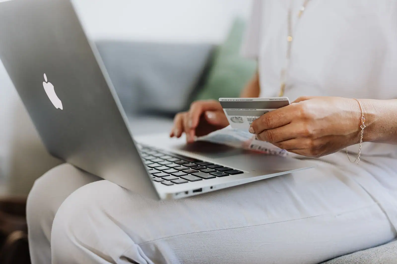 Personne tenant une carte bancaire devant un ordinateur portable lors d'une opération bancaire en ligne