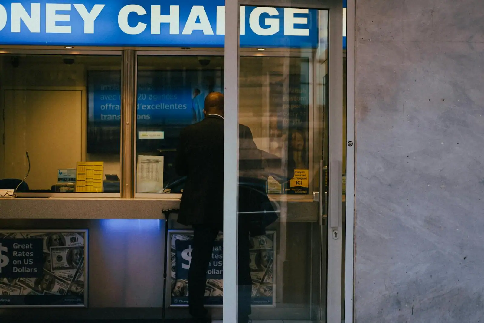 Un homme à un guichet de bureau de change de devises, illustrant la conversion de monnaie.