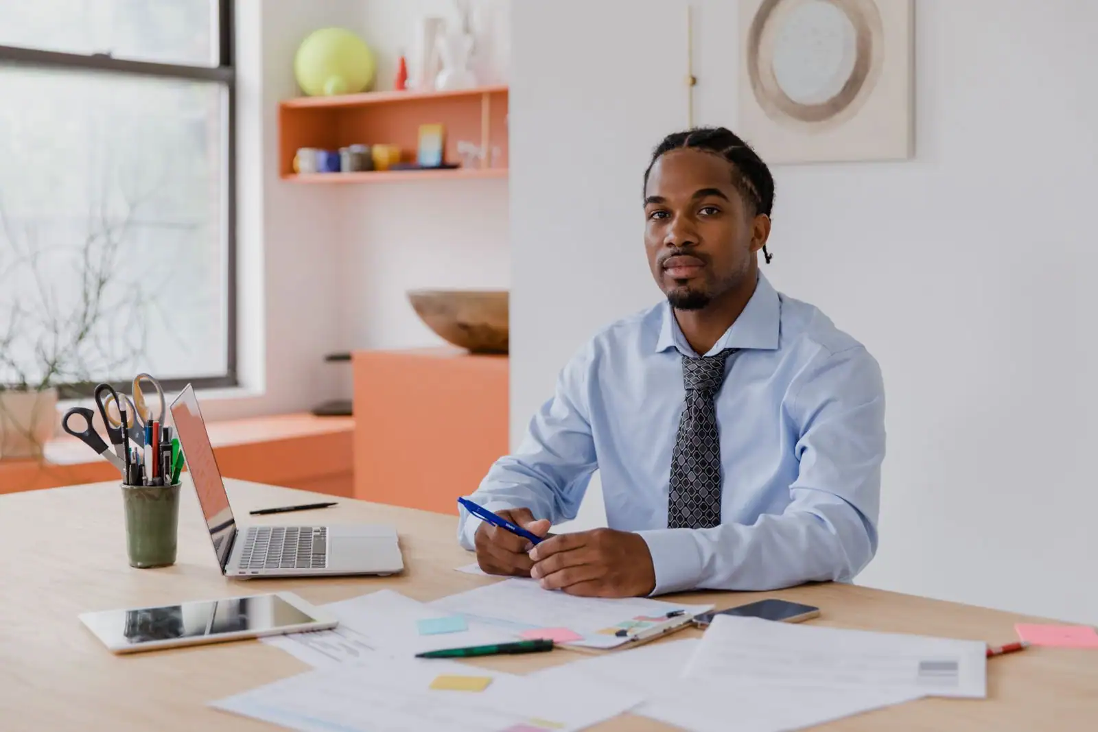 Un homme installé à son bureau avec un ordinateur portable et des documents de travail