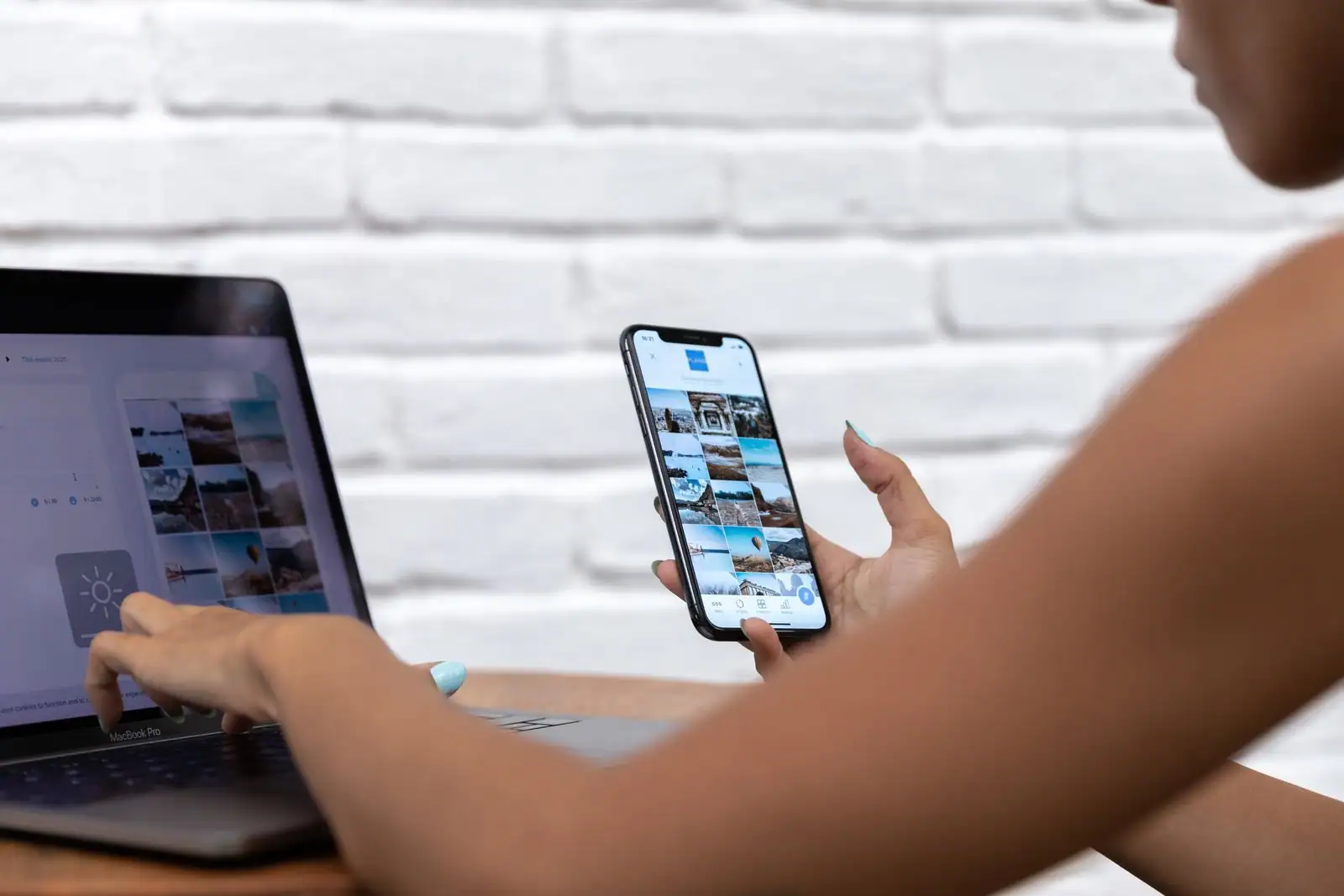 Personne gérant un fil de réseaux sociaux sur smartphone tout en travaillant sur un ordinateur portable