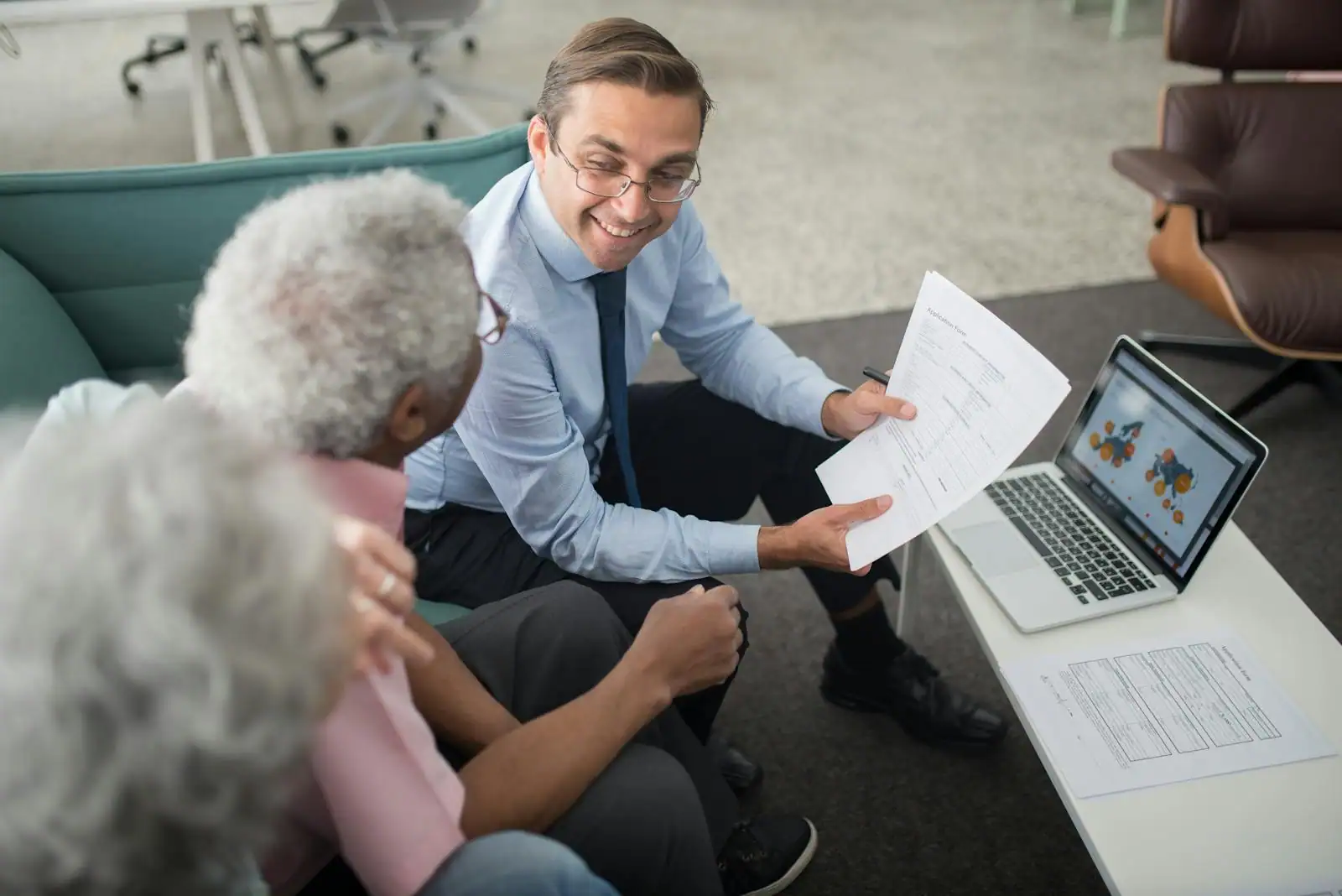 Un conseiller en gestion de patrimoine échange avec un couple autour de documents financiers