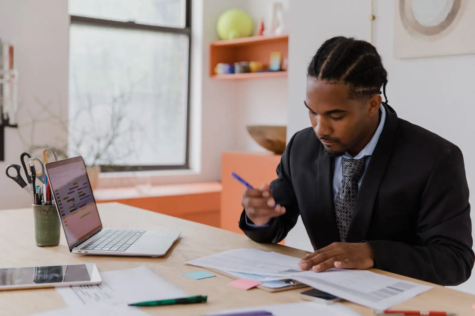 Dirigeant examinant des documents de gestion à son bureau, ordinateur portable ouvert à côté