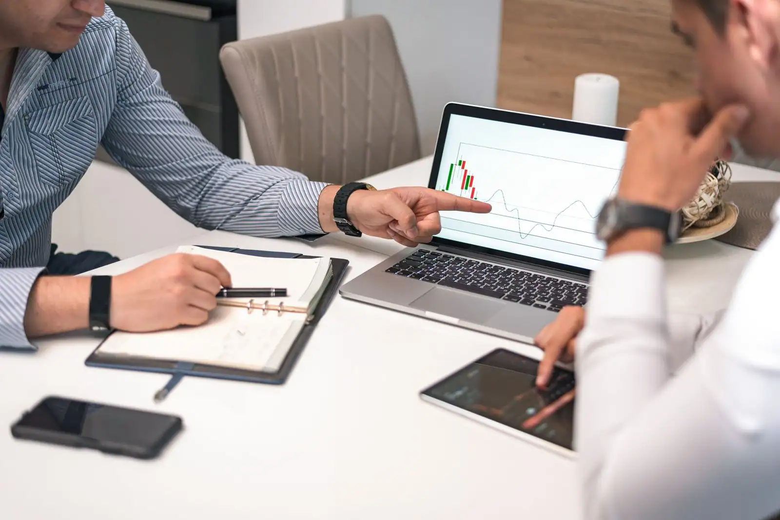 Deux personnes analysent un graphique affiché sur l'écran d'un ordinateur portable, lors d'une réunion de travail.