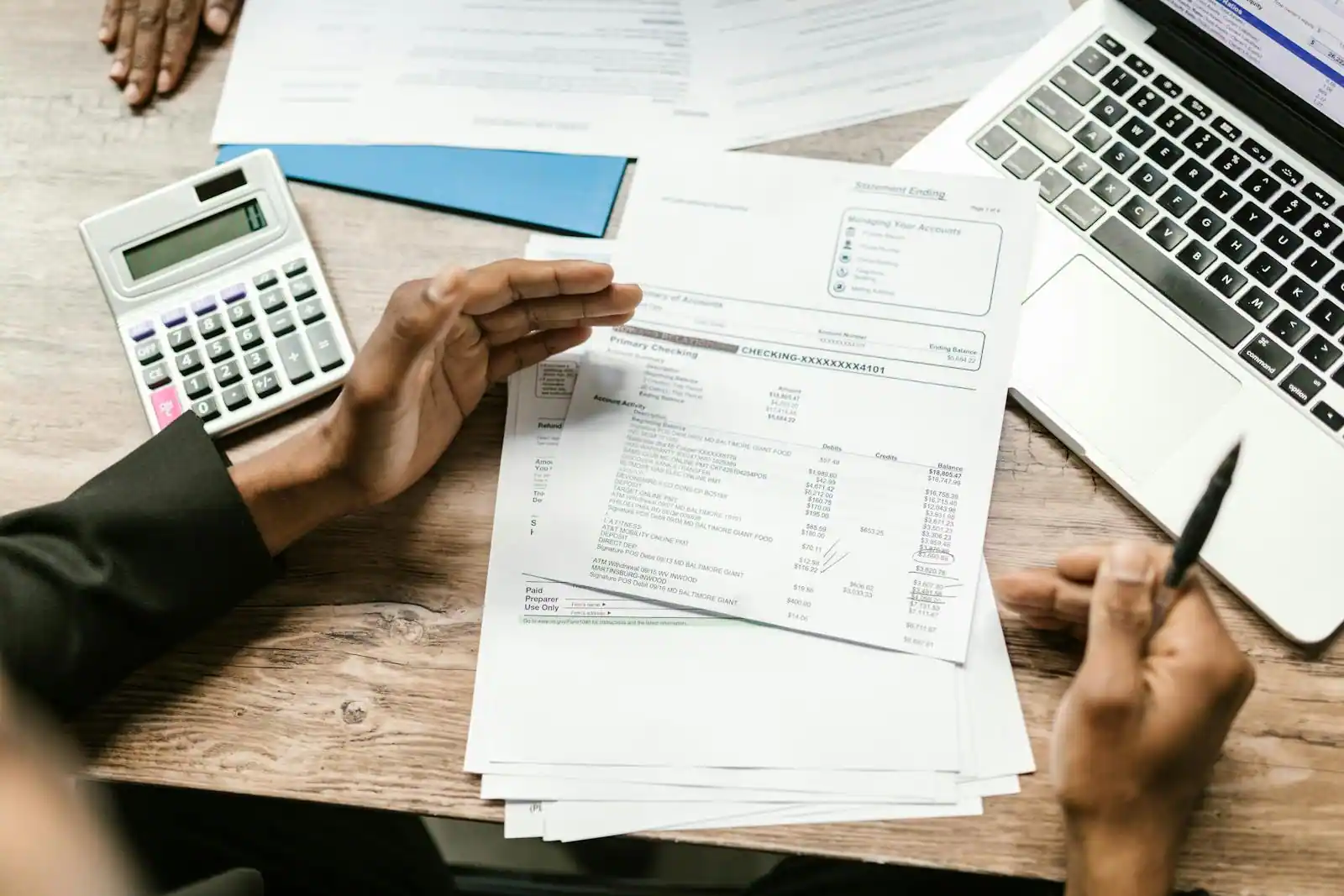 Personne calculant son impôt sur le revenu avec une calculatrice et un ordinateur portable