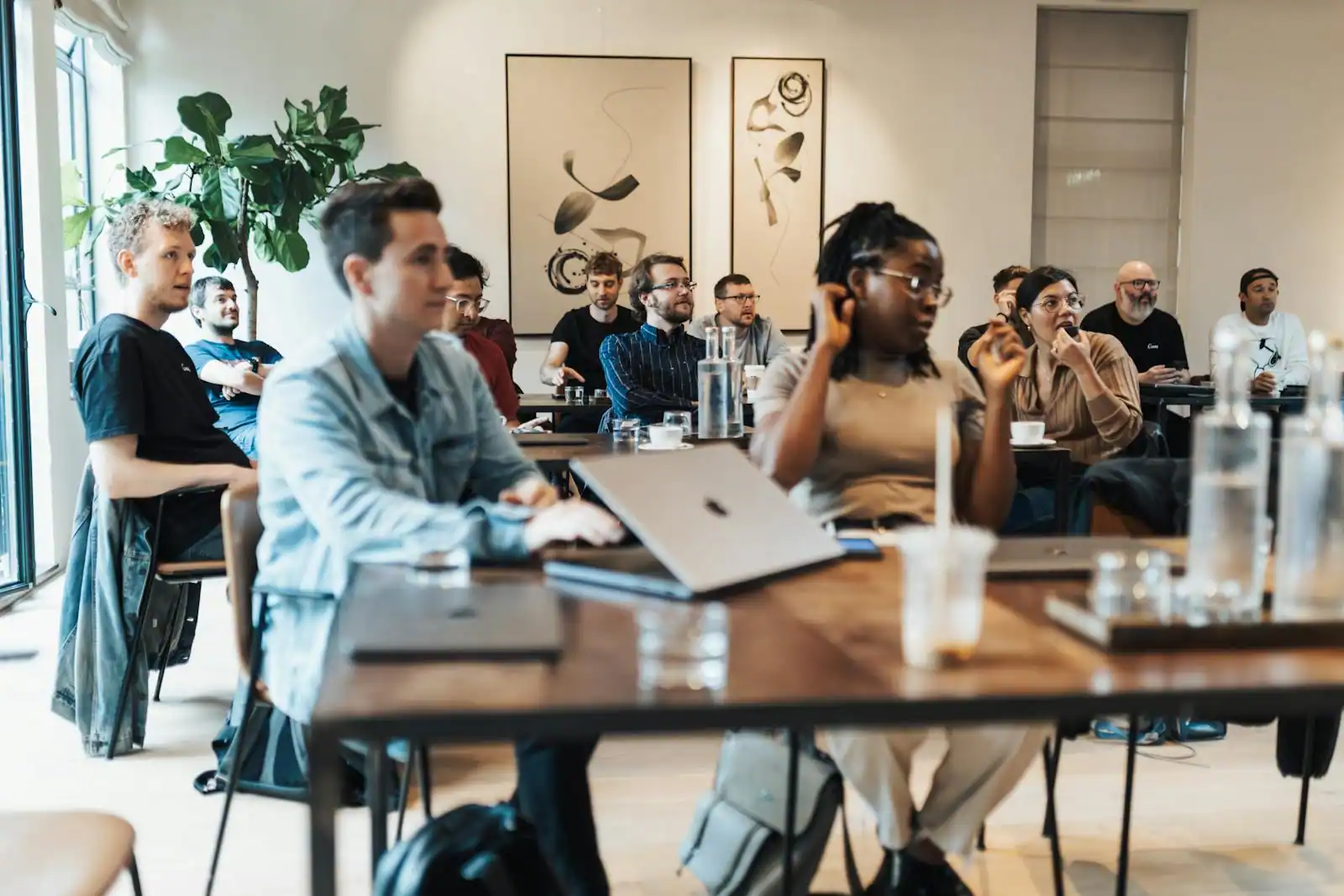 Un groupe d'adultes assis à des tables, ordinateurs portables ouverts, lors d'une session de formation