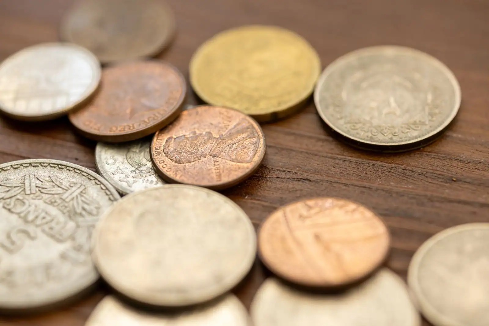 Pièces de monnaie anciennes posées sur une surface en bois, évoquant l'épargne