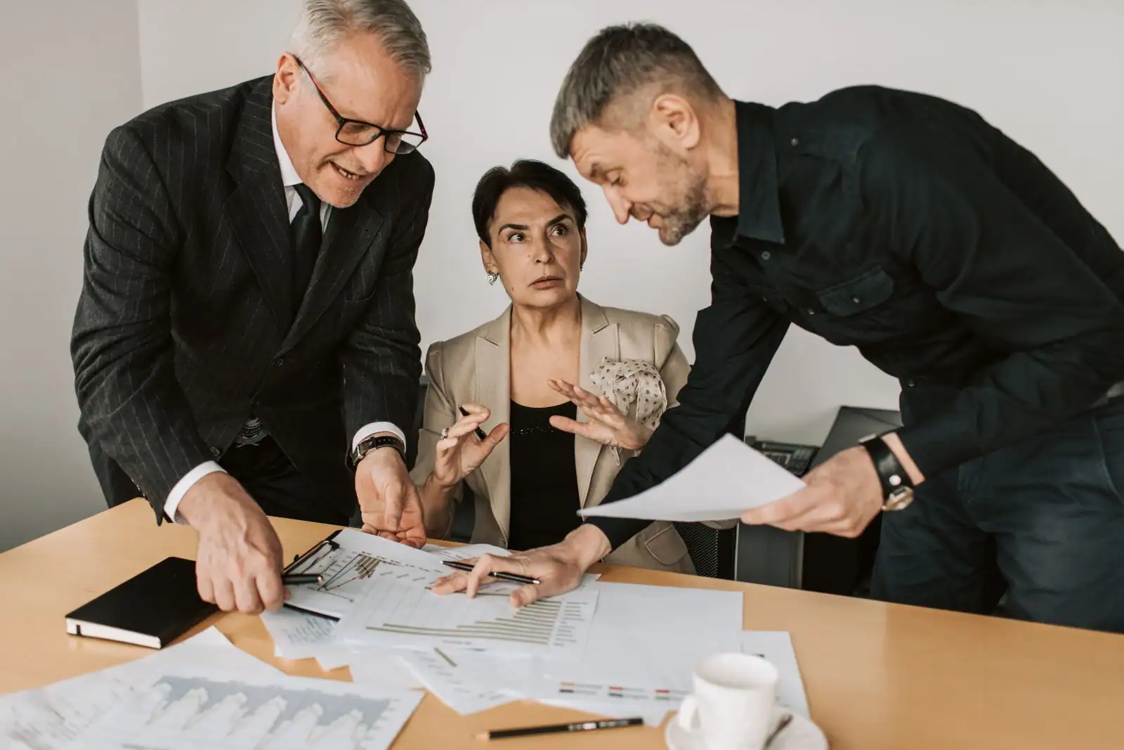 Salariée en discussion sérieuse avec deux responsables penchés sur des documents de travail.