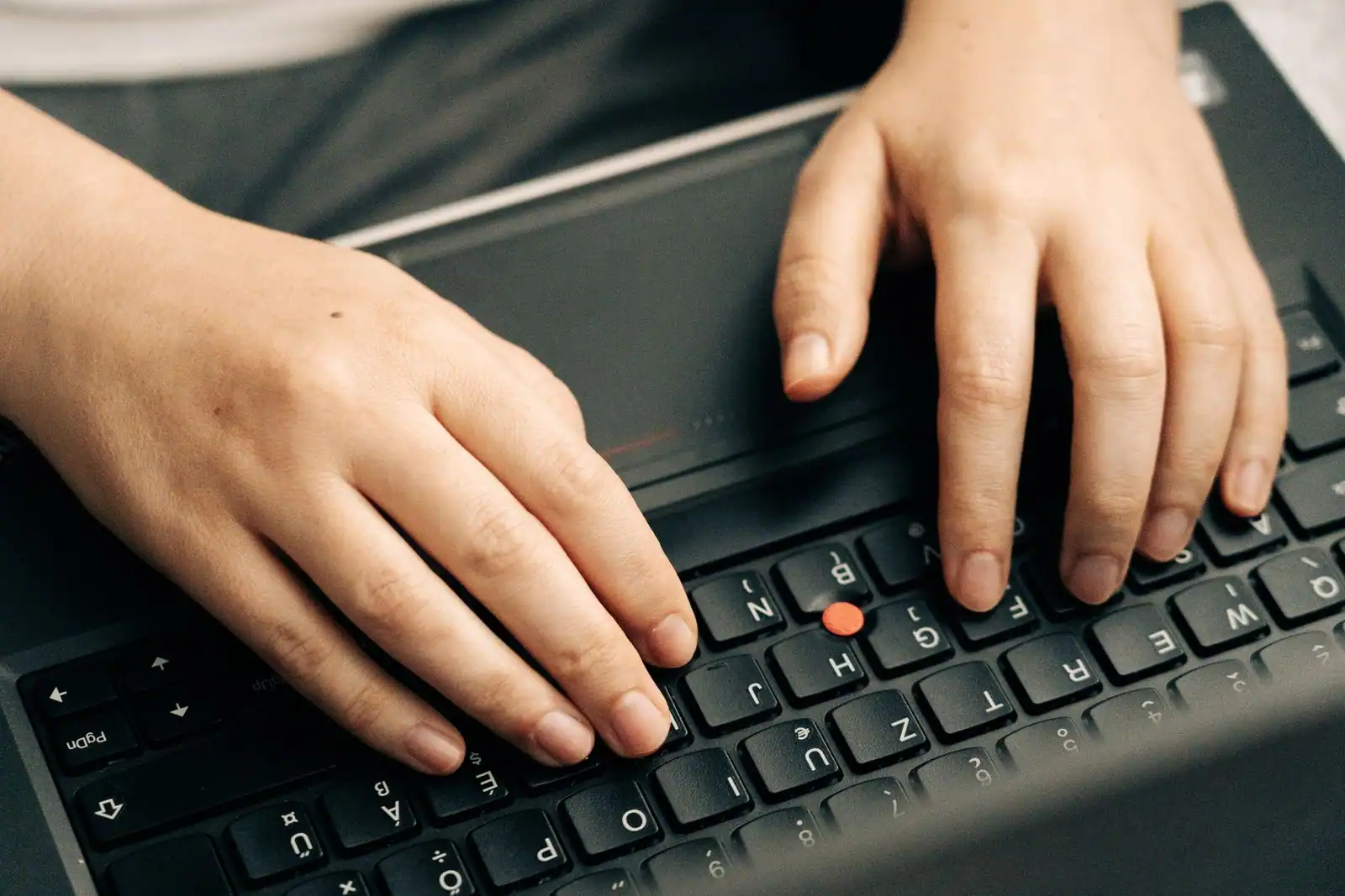 Gros plan sur les mains d'une personne en train de taper sur le clavier noir d'un ordinateur portable