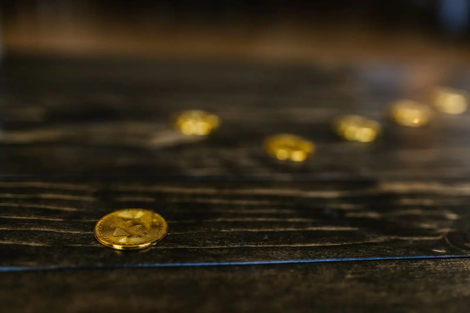Pièce physique dorée de crypto-monnaie de type bitcoin posée sur une surface en bois