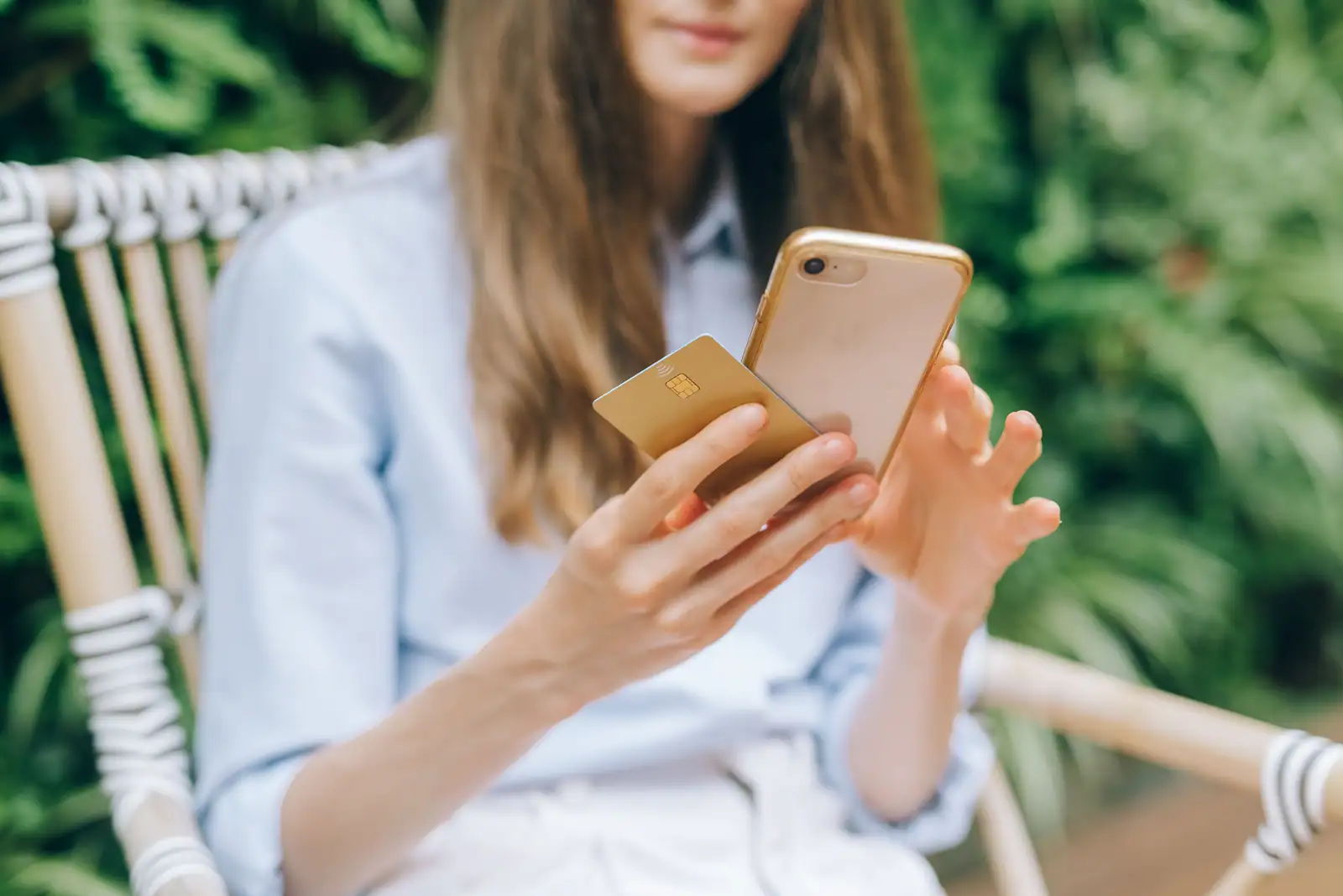 Femme tenant un smartphone et une carte bancaire à puce, en extérieur, en train de gérer un paiement mobile