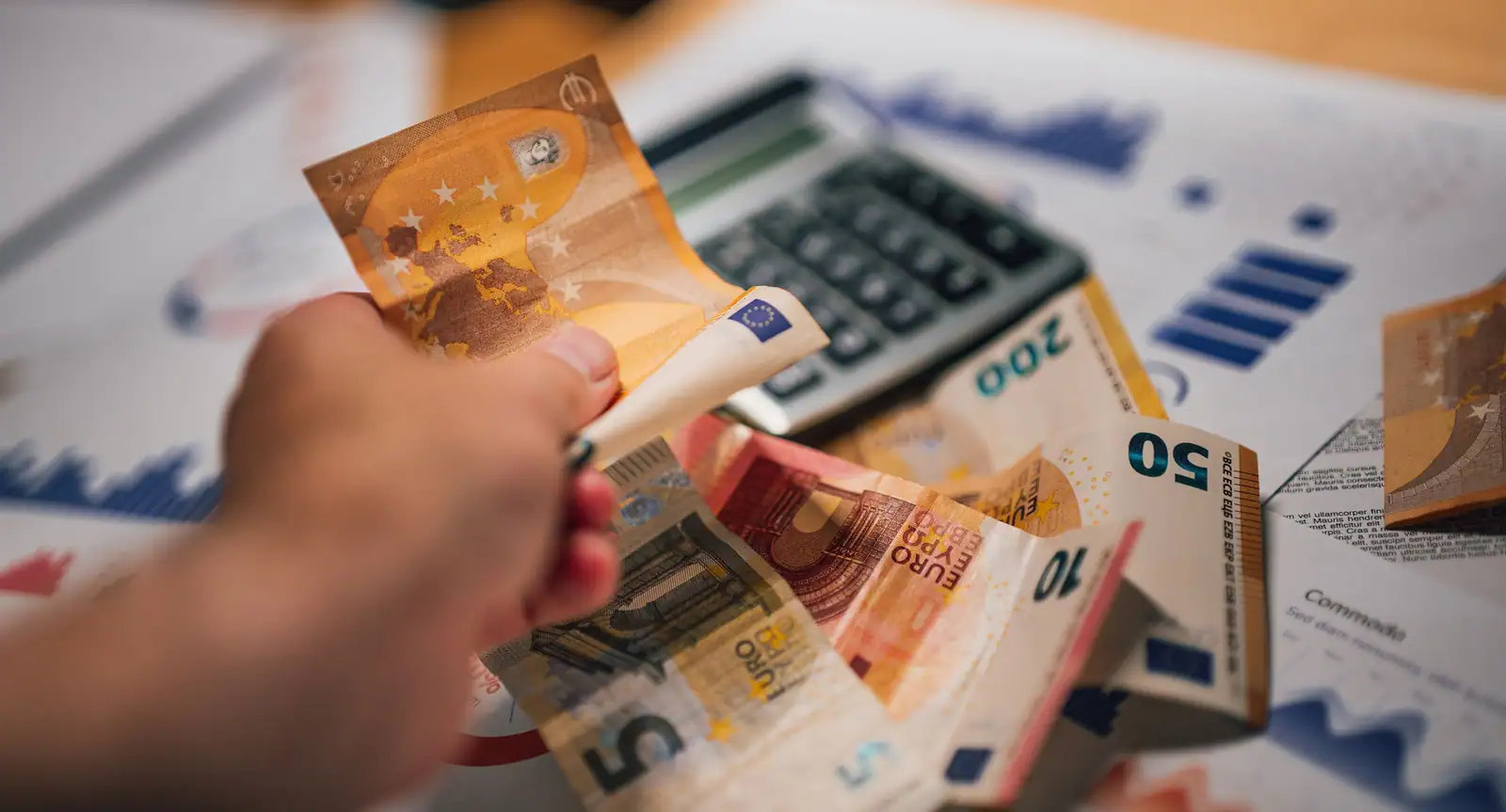 Billets en euros au-dessus de documents financiers et d’une calculatrice, préparation d’une épargne