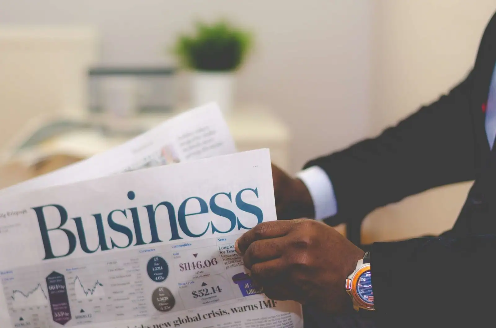 Personne en costume lisant les pages économiques d'un journal, avec cours de marché et indicateurs financiers
