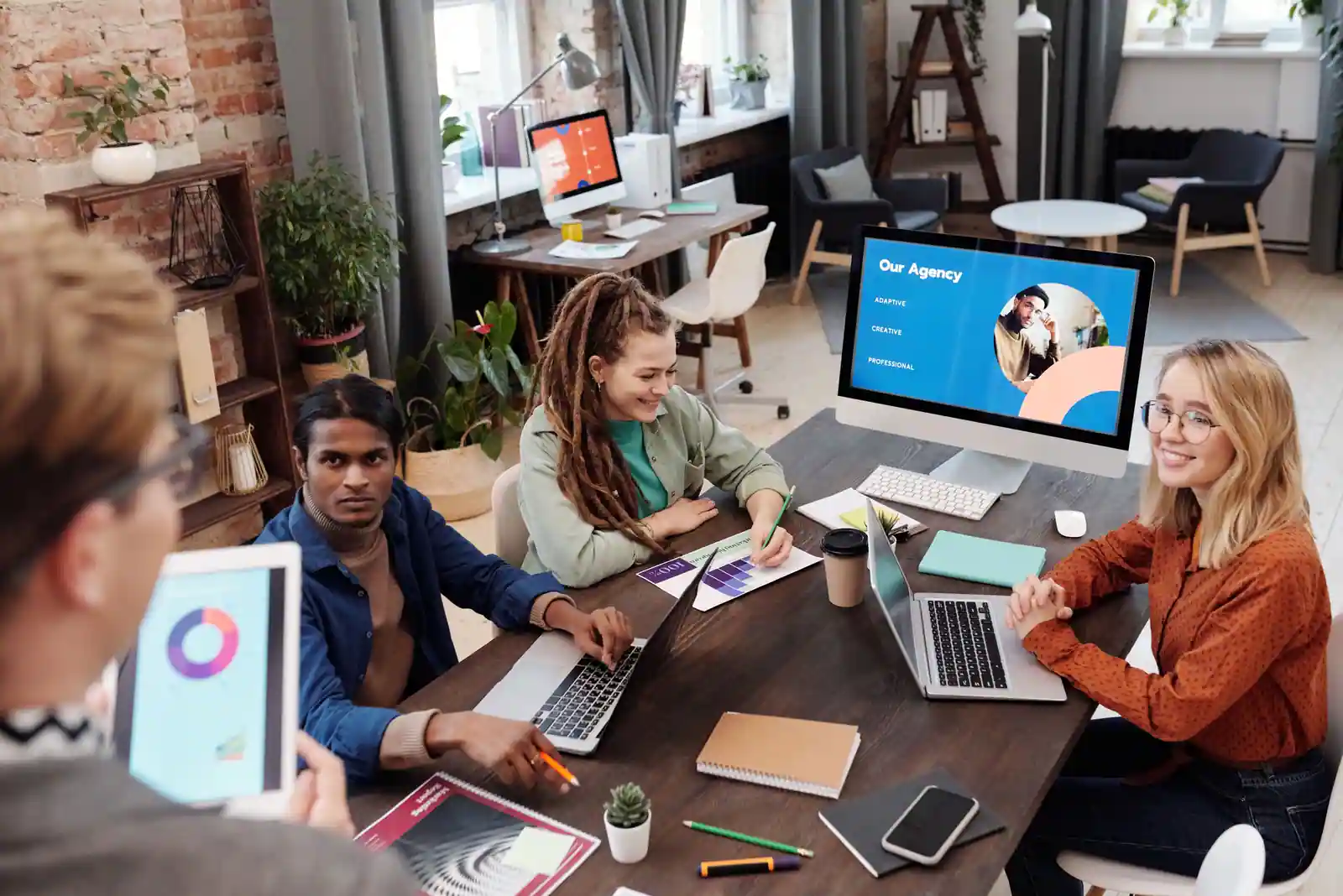 Équipe d'une agence de communication digitale réunie devant des écrans pour présenter sa stratégie.