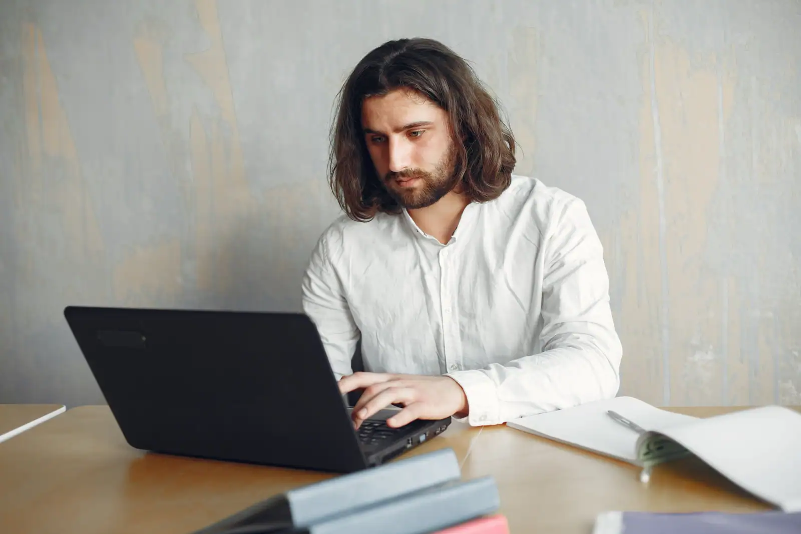 Un traducteur concentré tape sur son ordinateur portable, entouré de documents à son bureau.
