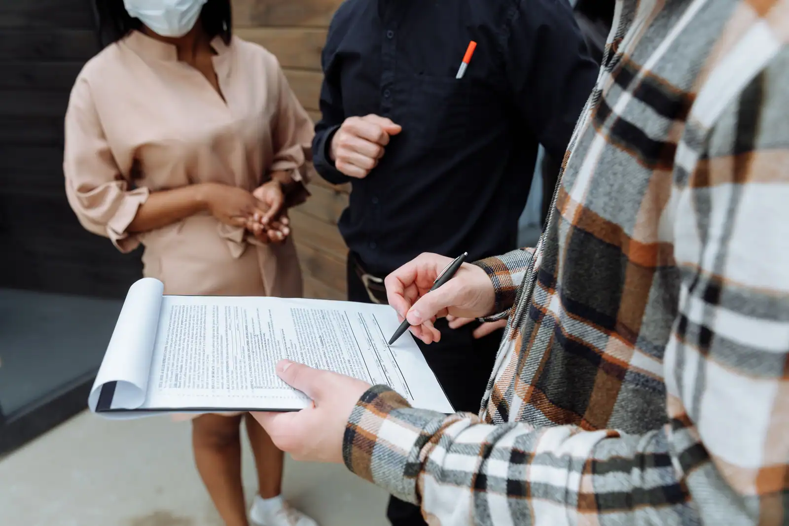 Trois professionnels signant ensemble un document dans un cadre de bureau.