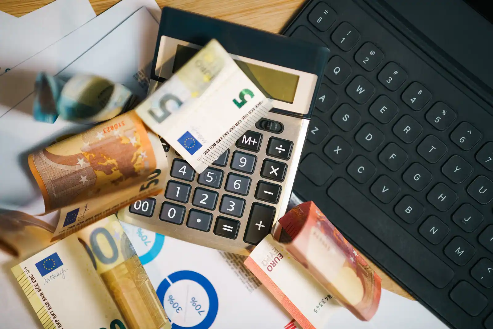 Billets en euros, calculatrice et documents pour calculer un revenu foncier imposable