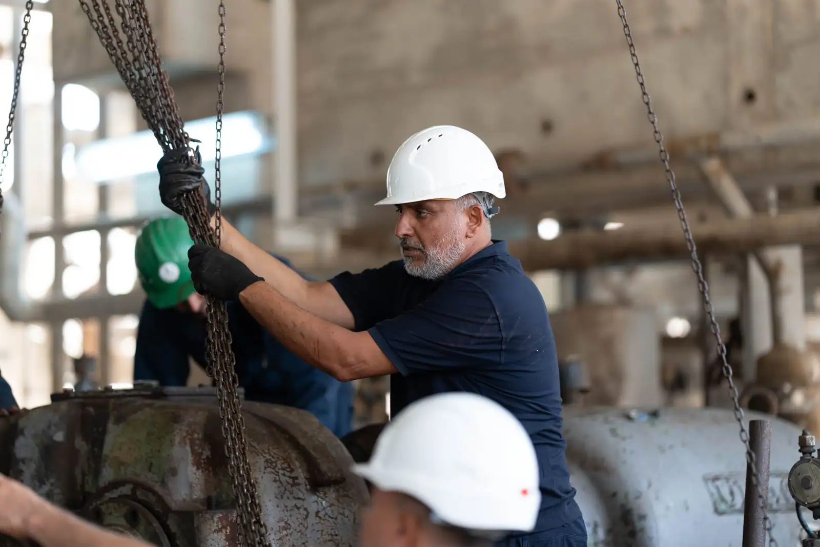 Des techniciens en casque de sécurité manœuvrent des chaînes sur un site industriel