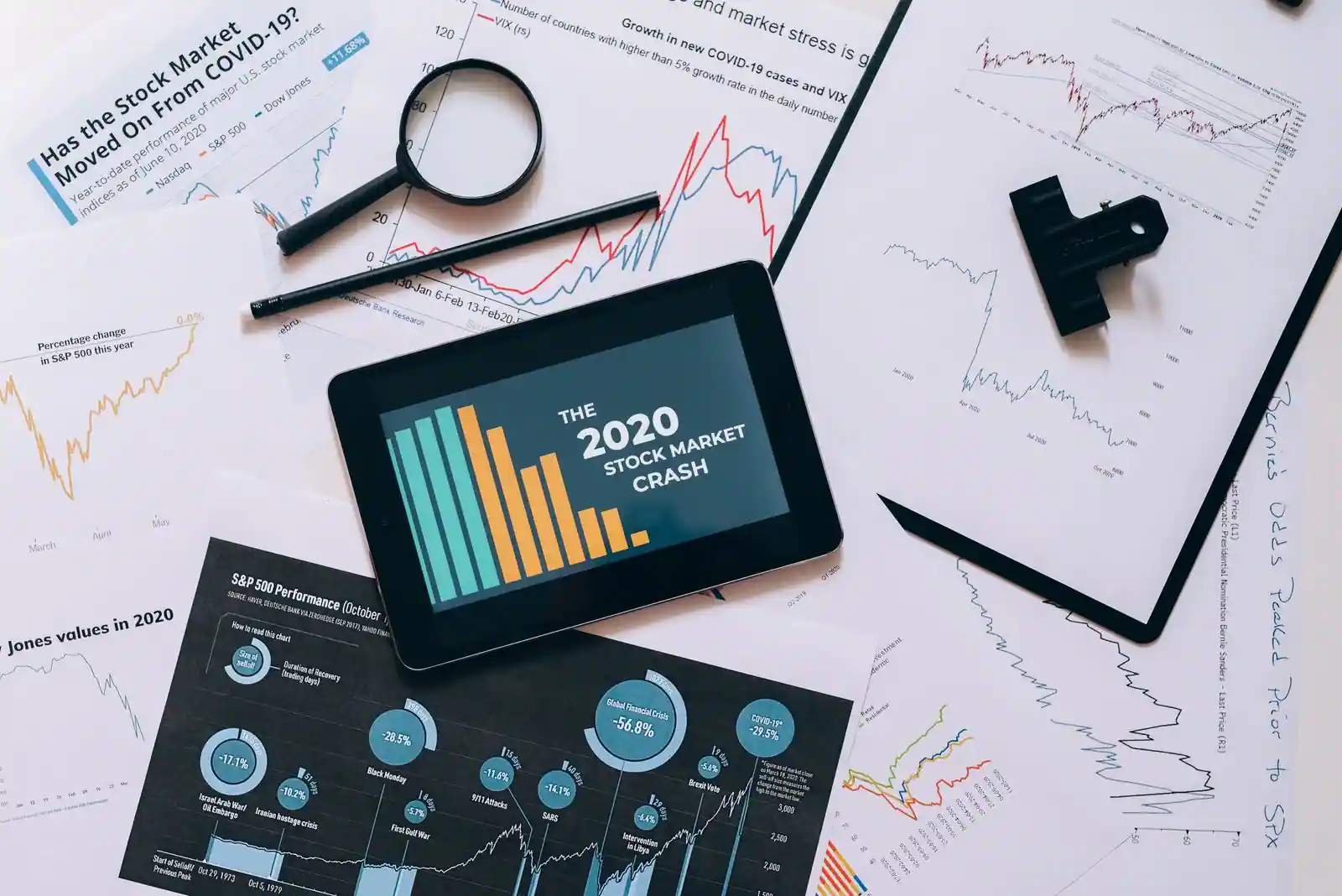 Personne qui consulte les cours de bourse sur une tablette, à côté d'un journal économique